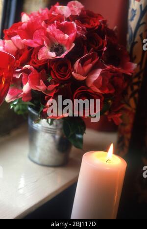 Mazzo di rose rosse e anemoni in secchio di fiori di metallo con candela - Foto Stock