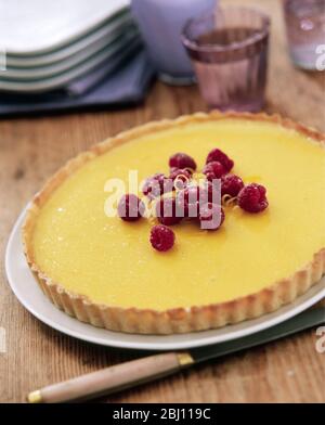 Crostata di limone con lamponi su tavolo rustico - Foto Stock