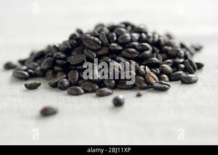 Piccolo mucchio di chicchi di caffè tostati scuri su tela - Foto Stock