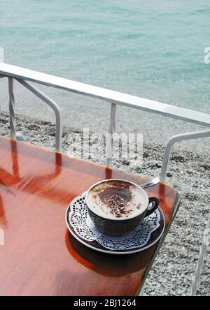 Tazza di cappuccino al tavolo del ristorante a lato della spiaggia, Amalfi, Italia -