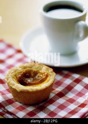 Tradizionale crostata inglese alla crema di crema su tovaglia di gingham rosso con tazza di caffè nero - Foto Stock