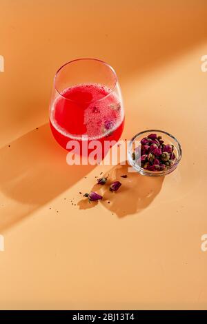 Cocktail alcolico rosa con limonata, champagne o Martini decorato con rosemite secche su sfondo colorato con riflessi sullo sfondo Foto Stock