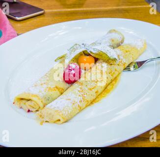crepes ripieno di cioccolato e bacche con fragole selvatiche e gooseberi di capo Foto Stock