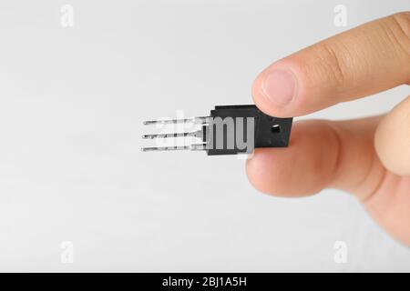 Dita maschio che tengono il microchip isolato su bianco Foto Stock