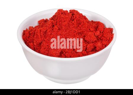 Pepe rosso (polvere di paprika) spruzzato in una ciotola bianca e isolato su uno sfondo bianco Foto Stock