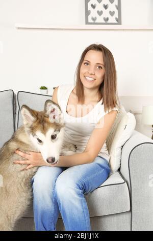 Ritratto di giovane donna e del suo cane malamuto in camera Foto Stock