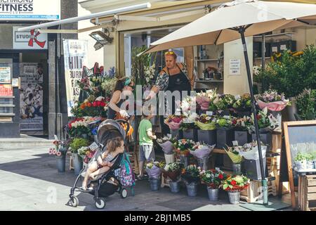 Londra/UK-1/08/18: Una madre con un figlio e una figlia nel passeggino che acquista un mazzo di fiori in un chiosco di fiori in una strada a Londra Foto Stock