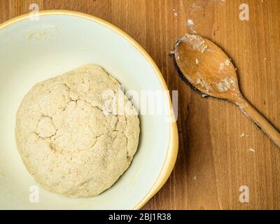 Pasta di pane OAT fatta forma forte farina di pane bianco con schiuma di avena e avena arrotolata in una terrina di miscelazione con un cucchiaio di legno Foto Stock