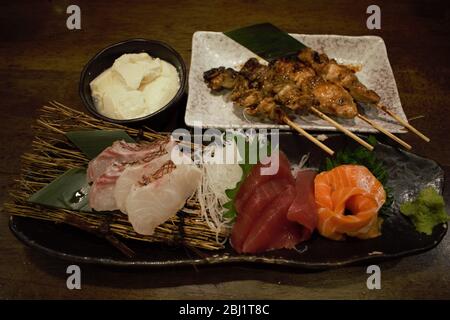 Tofu fresco, pollo spiedato Yakitori e sashimi assortiti presso un Izakaya a Tokyo, Giappone Foto Stock