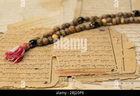 Perline di preghiera musulmana con pagine antiche del Corano. Concetti islamici e musulmani. Antichi fogli di carta del libro arabo Foto Stock