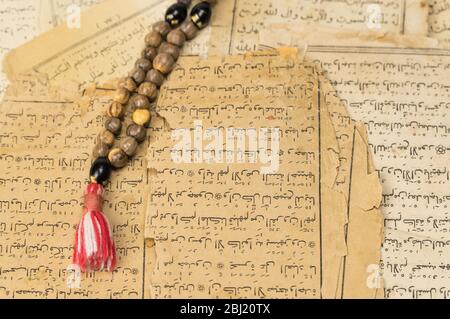 Perline di preghiera musulmana con pagine antiche del Corano. Concetti islamici e musulmani. Antichi fogli di carta del libro arabo Foto Stock