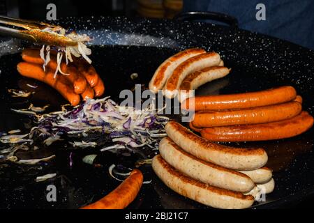 Tedesco barbecue salsicce alla griglia essendo da un fornitore nel mercato di Borough, Southwark, Londra UK Foto Stock