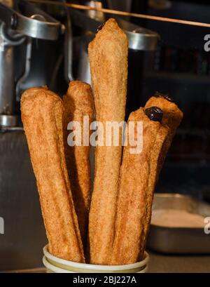 Churros con zucchero in polvere e cannella in un bagno di cioccolato fuso. Foto Stock