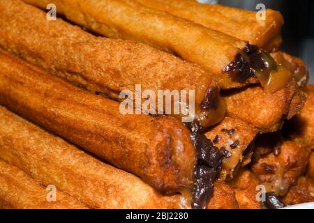 Churros con zucchero in polvere e cannella in un bagno di cioccolato fuso. Foto Stock