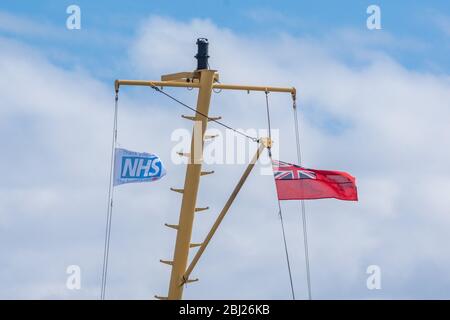 NHS, Thank You Heroes bandiera, con il cartello rosso che vola su Mast su Calmac Ferry Lord of the Isles in South Uist Outer Ebrides, Scozia Foto Stock