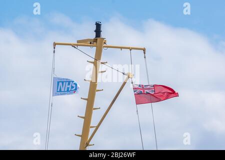 NHS, Thank You Heroes bandiera, con il cartello rosso che vola su Mast su Calmac Ferry Lord of the Isles in South Uist Outer Ebrides, Scozia Foto Stock