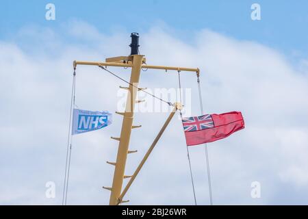 NHS, Thank You Heroes bandiera, con il cartello rosso che vola su Mast su Calmac Ferry Lord of the Isles in South Uist Outer Ebrides, Scozia Foto Stock