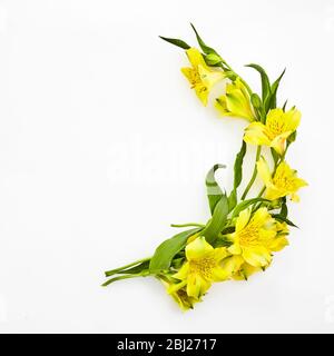 Mobile piatto con fiori gialli cornice rotonda su sfondo bianco. Sfondo estivo. Appartamento, vista dall'alto. Foto Stock