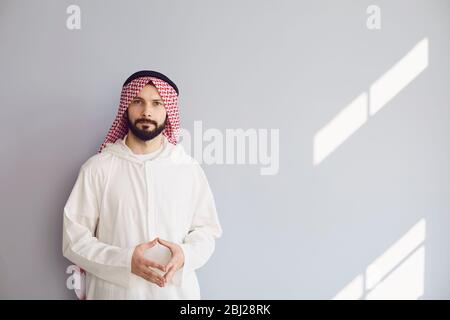 Uomo d'affari arabo sorridente ritratto su uno sfondo grigio Foto Stock