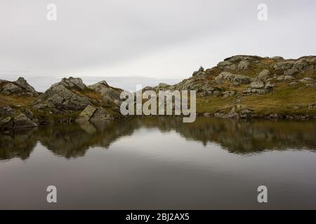 Laghetto naturale calmo nelle alpi austriache con riflessi speculari e tempo coperto Foto Stock