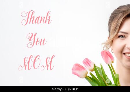 Mezza faccia bella donna sorridente con tulipani rosa su sfondo bianco con testo grazie mamma. Foto Stock