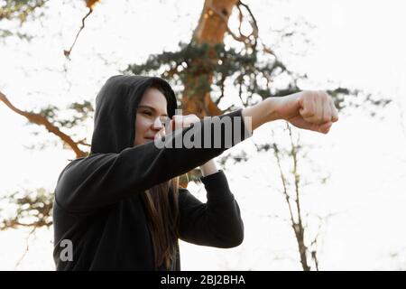 Giovane sport donna boxe nel parco. Giovane donna sta addestrando un colpo diretto, fuoco sugli occhi Foto Stock