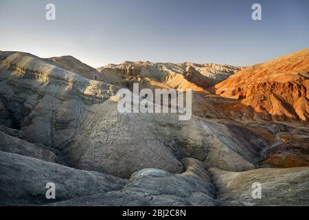 Piccola persona alle montagne al tramonto nel parco del deserto Altyn Emel in Kazakhstan Foto Stock