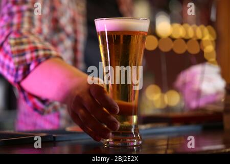 Barista che tiene un bicchiere di birra sul posto di lavoro Foto Stock