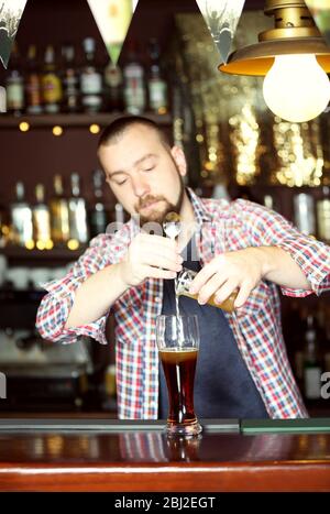 Il barista sta versando la birra nel bicchiere Foto Stock