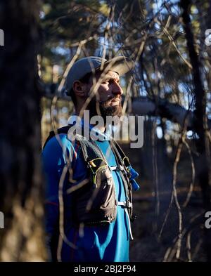 Ritratto di runner atleta con la barba in maglietta blu nella foresta Foto Stock