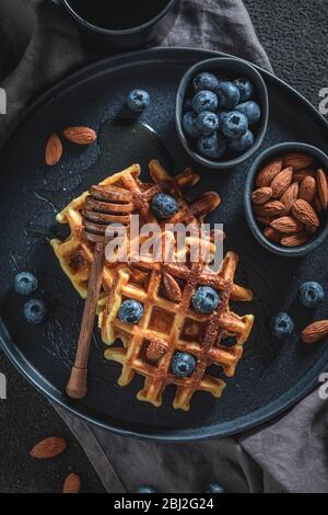 Gustosi waffle con miele, mirtilli e almont Foto Stock