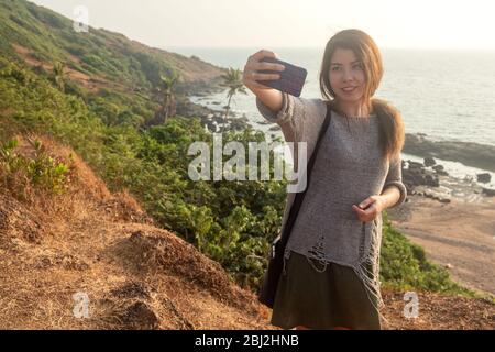 Giovane donna che viaggia intorno alla spiaggia costiera di Goan nella contea dell'India. Foto Stock