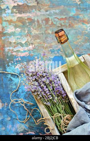 Scatola in legno con una bottiglia di champagne ghiacciato e un bouquet di lavanda. Regalo romantico. Foto Stock