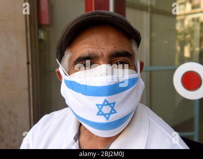 Gerusalemme, Israele. 28 Aprile 2020. Un israeliano indossa una maschera facciale obbligatoria con la bandiera nazionale, a causa della pandemia COVID-19, per il giorno della memoria e del giorno dell'Indipendenza, a Gerusalemme, martedì 28 aprile 2020. Foto di Debbie Hill/UPI Credit: UPI/Alamy Live News Foto Stock