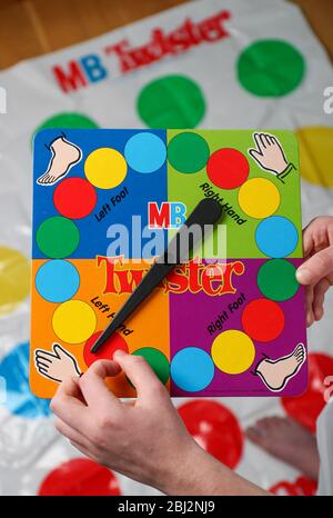 Un ragazzo che gira il gioco del twister girò prima che lui vada sul tappeto. Foto Stock
