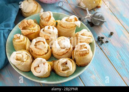 Torte fatte in casa, biscotti. Rotolo di biscotti di pasta sfoglia ripieni di zucchero a velo in una ciotola su un tavolo di legno. Spazio di copia. Foto Stock