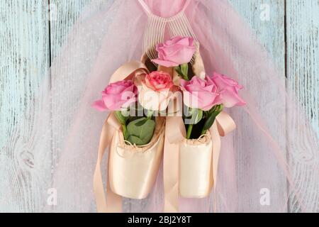 Scarpe da balletto decorate con rose appese su sfondo di legno blu Foto Stock