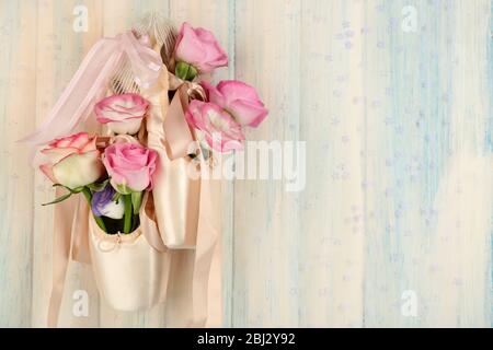 Scarpe da balletto decorate con rose appese su sfondo di legno chiaro Foto Stock