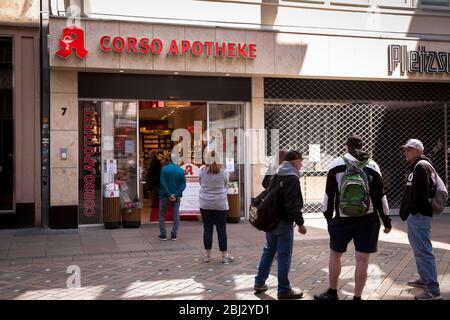 Coronavirus / Covid 19 focolaio, 16 aprile. 2020. Persone in coda di fronte a una farmacia sulla via dello shopping Westenhellweg, Dortmund, Germa Foto Stock