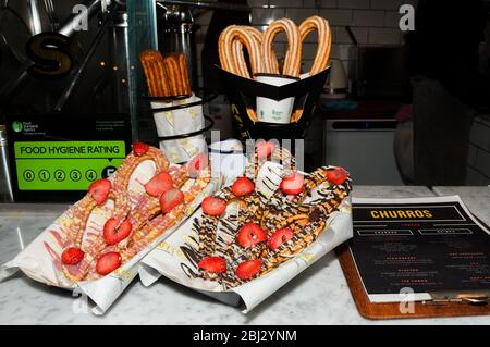 Churros con zucchero in polvere e cannella in un bagno di cioccolato fuso. Foto Stock