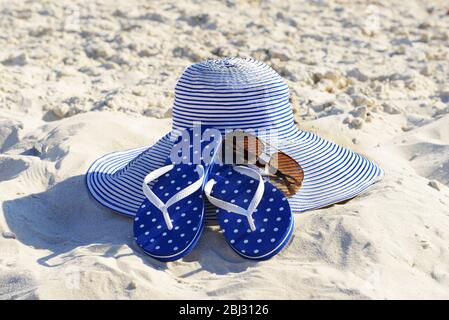 Infradito, occhiali da sole e cappello sulla spiaggia di sabbia closeup Foto Stock