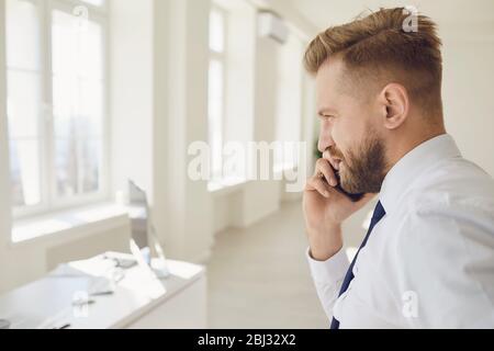 Uomo d'affari adulto sicuro che ha conversazione telefonica in ufficio Foto Stock