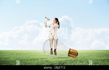 Business donna seduta sulla grande lampadina della luce Foto Stock