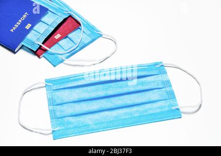 maschera facciale medica blu su sfondo bianco. sullo sfondo sono presenti due passaporti stranieri di colore blu e rosso con maschere nidificate. quaran mondo Foto Stock