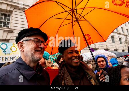 Il leader del lavoro Jeremy Corbyn si pone con un attivista sotto un ombrello arancione brillante prima di unirsi alla folla per marciare verso Piazza del Parlamento per celebrità Foto Stock