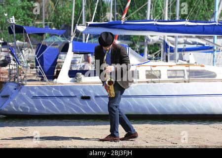 Bell'uomo suona sax davanti allo yacht Foto Stock