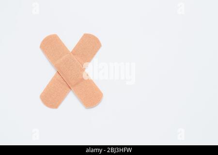 Bendaggio adesivo, medicazione per lesioni. Intonaci attaccati trasversalmente su sfondo bianco. Copia, spazio di testo Foto Stock