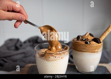 Dalgona caffè - caffè istantaneo o espresso in polvere montato con zucchero e acqua calda. Caffè freddo, montato, dalgona concetto. Foto Stock
