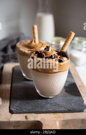 Dalgona caffè, una bevanda alla moda. Due bicchieri di caffè Dalgona su un asse di legno Foto Stock