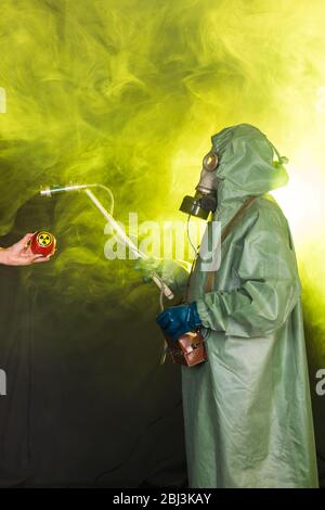 Concetto di radiazione, inquinamento e pericolo - uomo in abbigliamento protettivo e maschera a gas su sfondo scuro Foto Stock